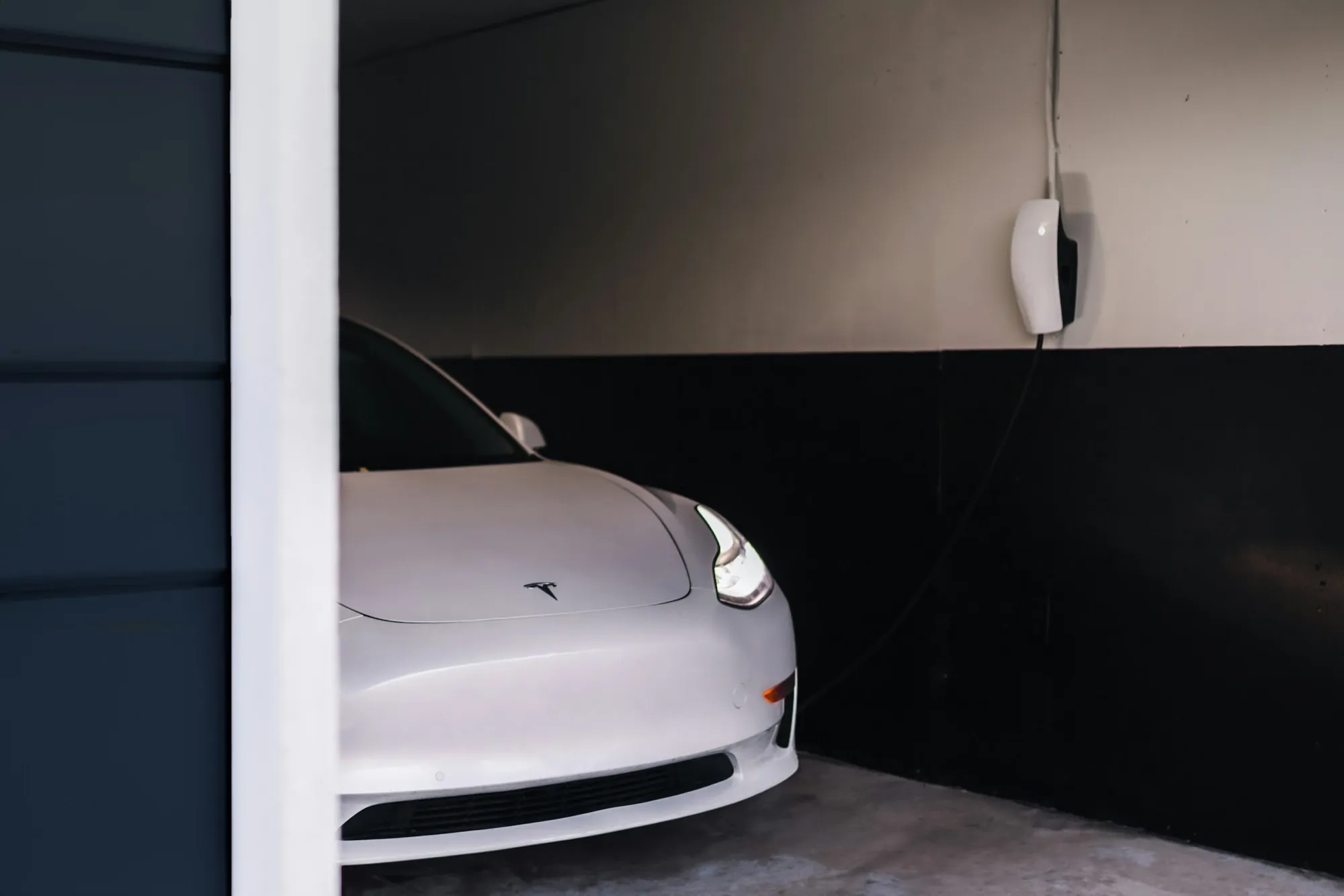 White Tesla Model 3 plugged into a home wall connector